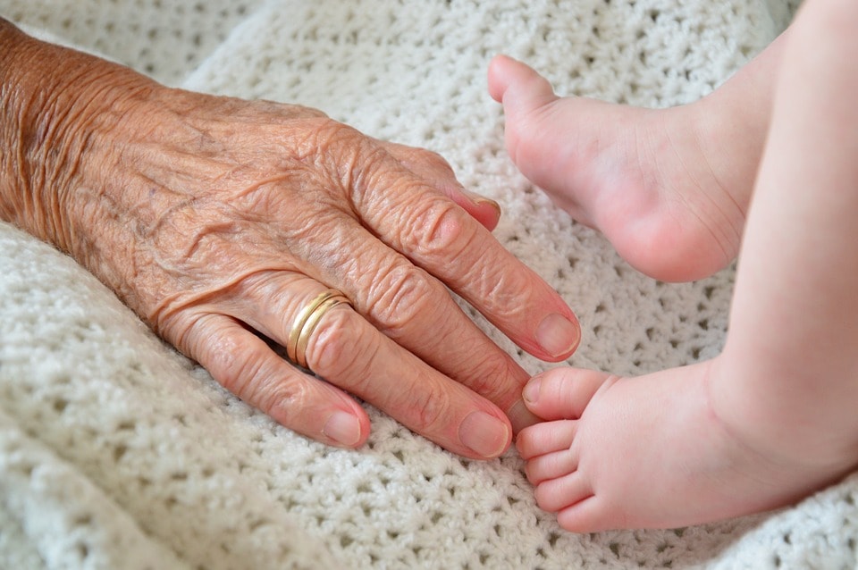 赤ちゃんの足を触ろうとするおばあちゃんの手